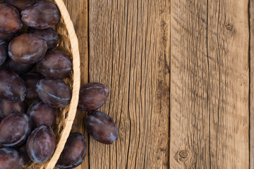 Plums in a basket on an old wooden table.