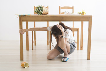 地震でテーブル下に避難する女性