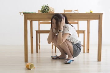 地震でテーブル下に避難する女性
