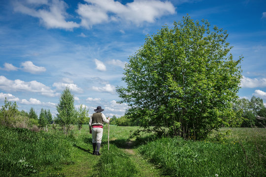 traveler in old clothes with a knapsack  on a country road