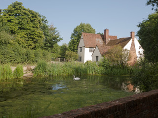 Beautiful view of Willy Lott's House Cottage at flatford mill suffolk national trust with river pond lake in front and grass and trees