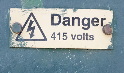 A metal sign plate on the box of electrical grid equipment station safety
