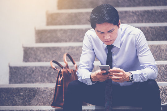 stressed businessman use smart phone sitting at stairway. worry about business situation