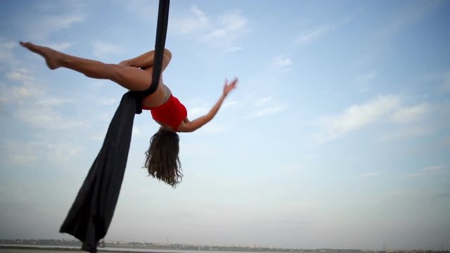 Happy girl dance with aerial silk on a sky background rapid slow motion