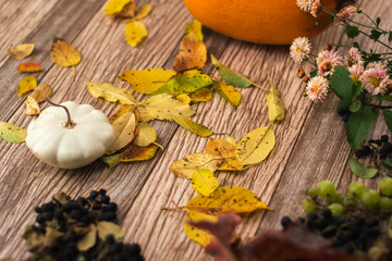 Autumn still life: pumpkin and autumn leaves on a wooden background.