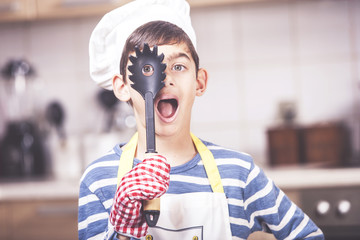 Funny little boy chef in the kitchen