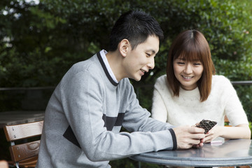 Fototapeta premium Young couple watching smartphone on cafe terrace