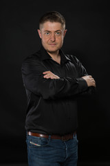 Young confident man portrait of a confident businessman showing by hands on a black background. Ideal for banners, registration forms, presentation, landings, presenting concept.