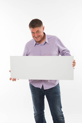 Young playful man portrait of a confident businessman showing presentation, pointing paper placard gray background. Ideal for banners, registration forms, presentation, landings, presenting concept.