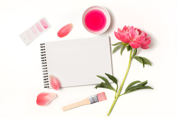 Empty open notebook mockup with pink peony flower and painting supplies. Blank paper letter on...