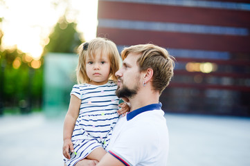 Young father holds the little daughter on hands.