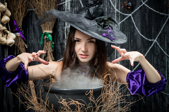 Evil witch in a hat cooks a potion in a cauldron