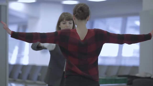 Airport Worker Scans A Young Woman With Hand Scanner In The Airport