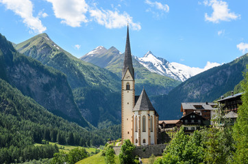Heiligenblut, Carinthia, Austria, A scenic landscape photo of the Austrian municipality of Heiligenblut with St. Vincent Church in front of the Hohe Tauern mountains. - obrazy, fototapety, plakaty
