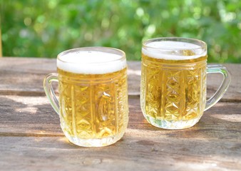 Two Glasses of cider or light beer and bottle on rustic wooden background octobcrfest
