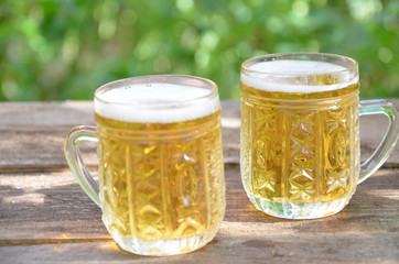 Two Glasses of cider or light beer and bottle on rustic wooden background octobcrfest