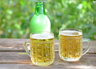 Two Glasses of cider or light beer and bottle on rustic wooden background octobcrfest