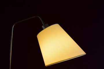 Simple, but beautiful lampshade with light on. Black background. Horizontal image.