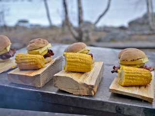 Homemad hamburgers and grilled corn on wooden plates. © jarnicek