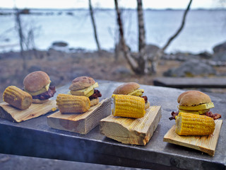 Homemad hamburgers and grilled corn on wooden plates. © jarnicek