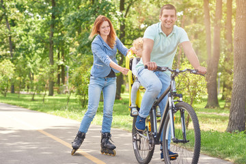 Shot of a happy man riding bicycle at the park with his baby in a bike seat and his wife rollerblading copyspace family activity sports recreation leisure weekend holidays.