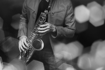 Obraz premium Saksofonista jazzowy w wykonaniu na scenie. Dodano filtr kolorów i sześciokątny efekt bokeh.