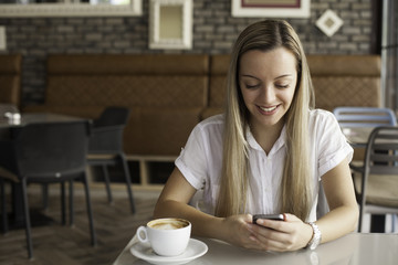 Young beautiful woman using phone in urban cafe