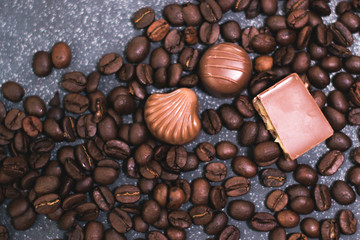 Coffee beans and tiles of dark chocolate on a dark matte background.