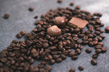 Coffee beans and tiles of dark chocolate on a dark matte background.