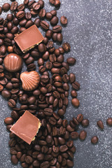 Coffee beans and tiles of dark chocolate on a dark matte background.