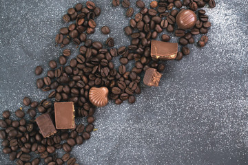 Coffee beans and tiles of dark chocolate on a dark matte background.