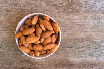 White ceramic bowl with almond on the wooden background
