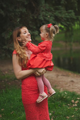 happy mother with daughter in red dresses