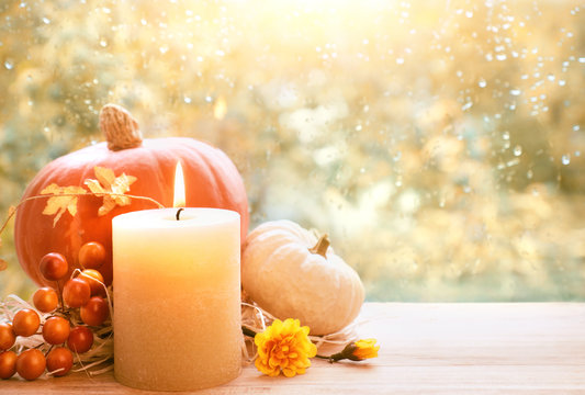 Burning candle, pumpkin and Fall decorations on a windowboard, space