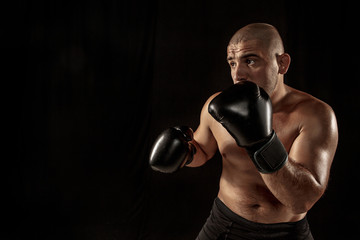 The young man kickboxing on black