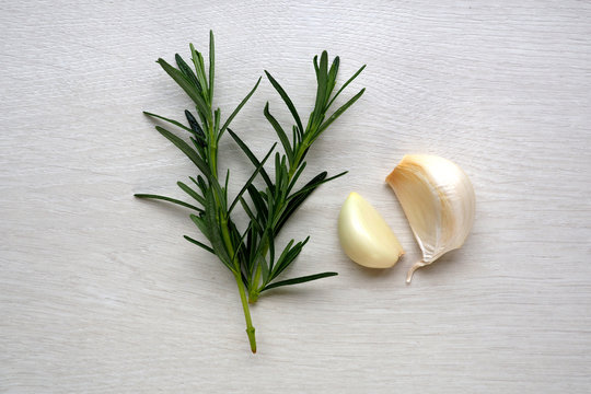Rosemary and garlic on white wood background