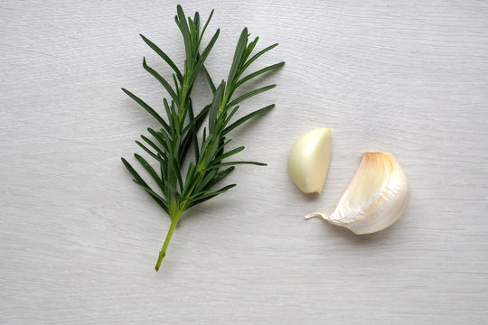 Rosemary and garlic on white wood background