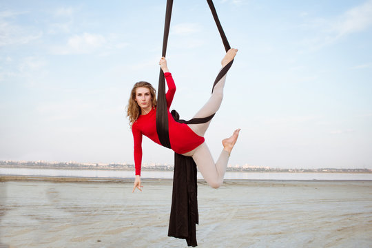 Fit woman in skinny skinny clothes dancing with aerial silk on a sky background, gymnast training on aerial silk 