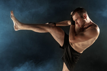 Obraz premium The young man kickboxing on black