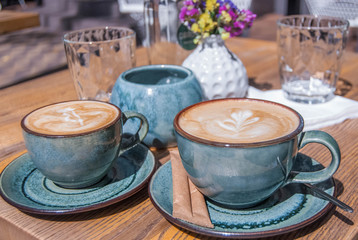 two cups of coffee with foam on the table in a café