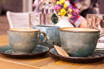 two cups of coffee with foam on the table in a café