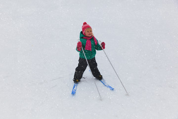 little girl learning to ski in winter