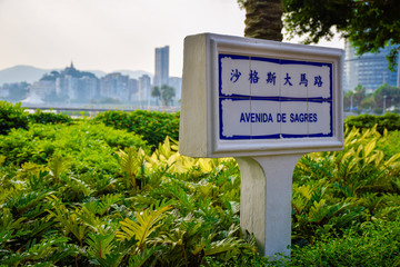 The street sign; made of white porcelain tiles with blue Portuguese lettering, with Penha hill as a background, Macau