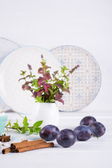 Group of fresh purple  plums on a white kitchen table ready for cooking