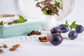 Group of fresh purple  plums on a white kitchen table ready for cooking