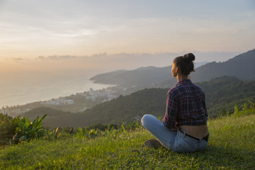 Naklejka na ściany i meble Hipster young girl enjoying sunset on peak mountain. Tourist traveler on background valley landscape view mockup.