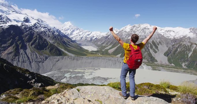 New Zealand hiker travel nature hiking man winning with arms up in success. Adventure outdoors tramping backpacker cheering at view of Mt Cook in Aoraki / Mount Cook National Park. RED EPIC.