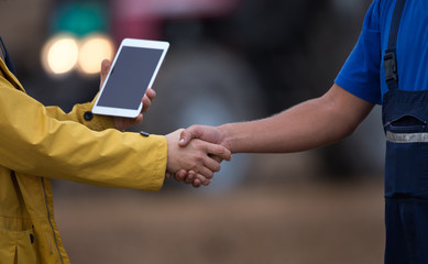 Farmers shaking hands in field