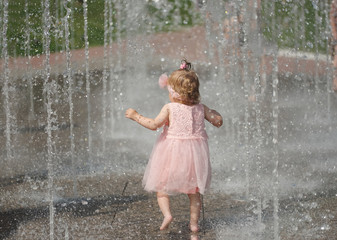 little girl plays with water in fountain