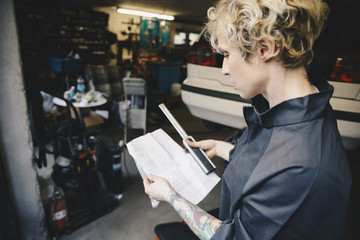 Side view of female mechanic reading checklist at auto repair shop